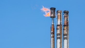 Photo depicts Burning oil flare on a blue sky